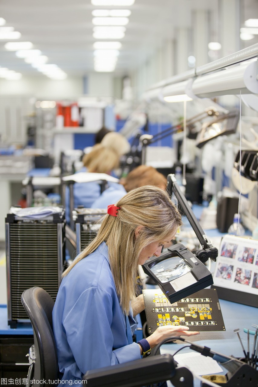 技术人员检查印刷电路板在高科技电子制造工厂
